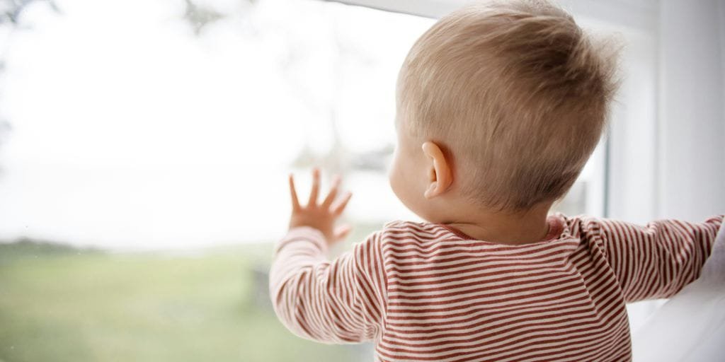 child in red and white striped shirt looking out the window