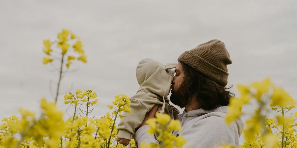 a man and woman kissing in a field of yellow flowers