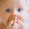 selective focus photography of baby holding wooden cube