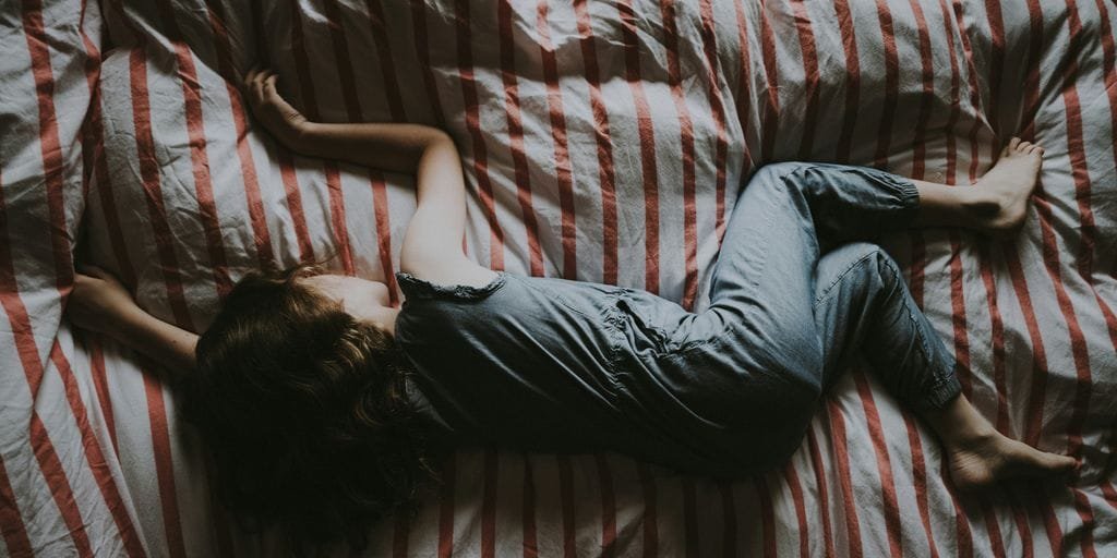 kid sleeping on red and gray bed